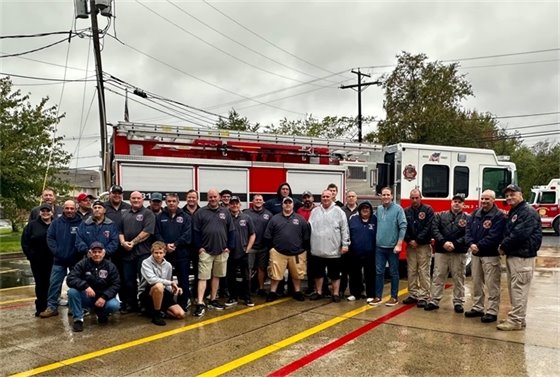 Group photo of firefighters, Mayor Perry, and Committeeman and Ex-Fire Chief Ryan Clarke in front of the engine