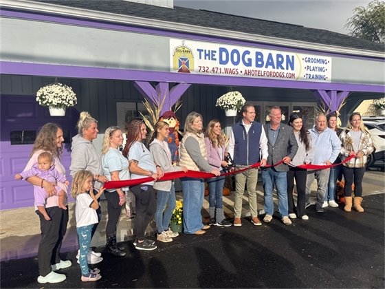 Group photo of ribbon cutting in front of The Dog Barn and Groom